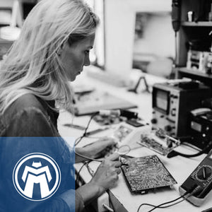 Black and white photo of blond woman working on circuit board.