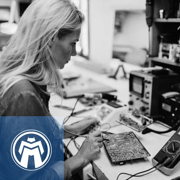 Black and white photo of blond woman working on circuit board.